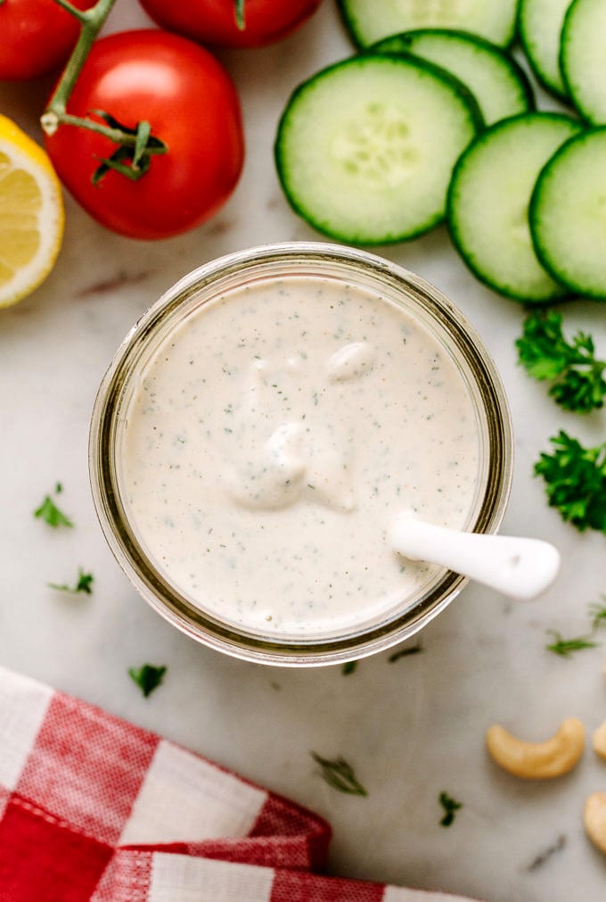 top down view of creamy vegan ranch dressing in a jar with items surrounding.