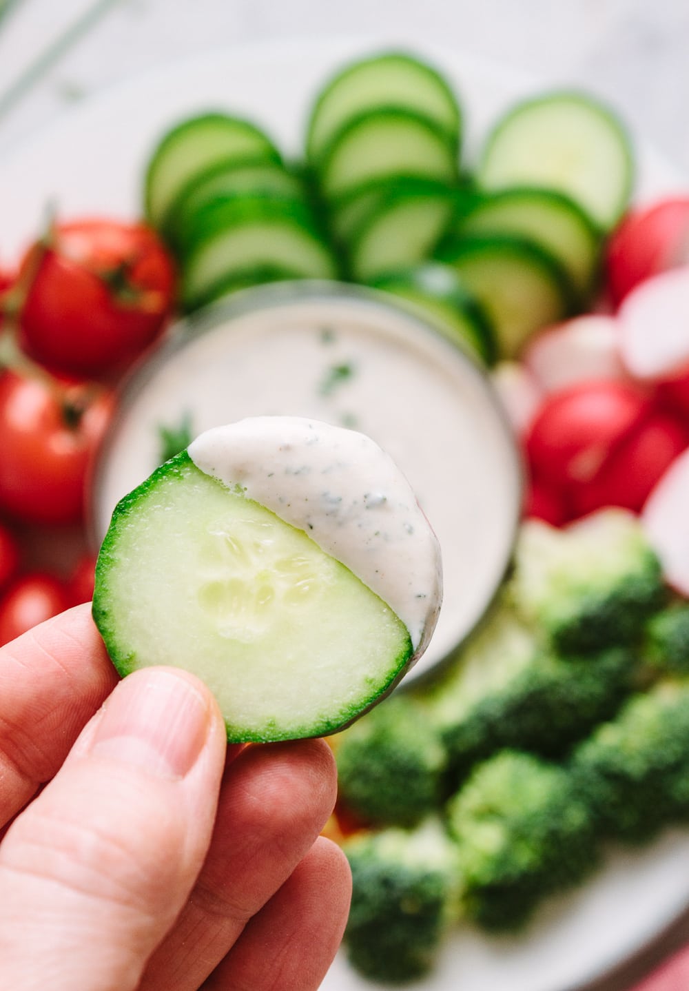 up close view of a sliced cucumber dipped in easy vegan ranch dip.