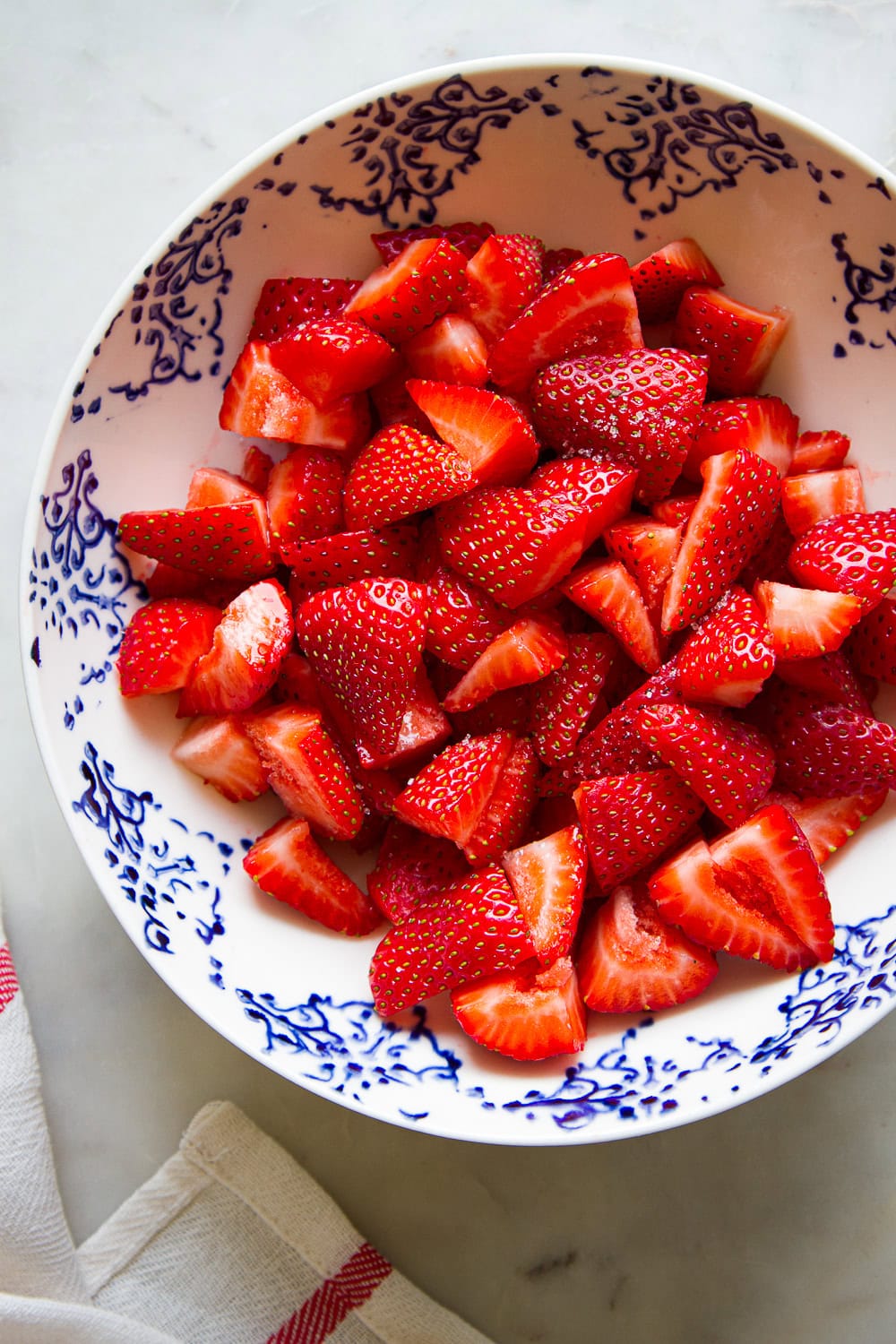 top down view of bowl of sliced strawberries macerating.