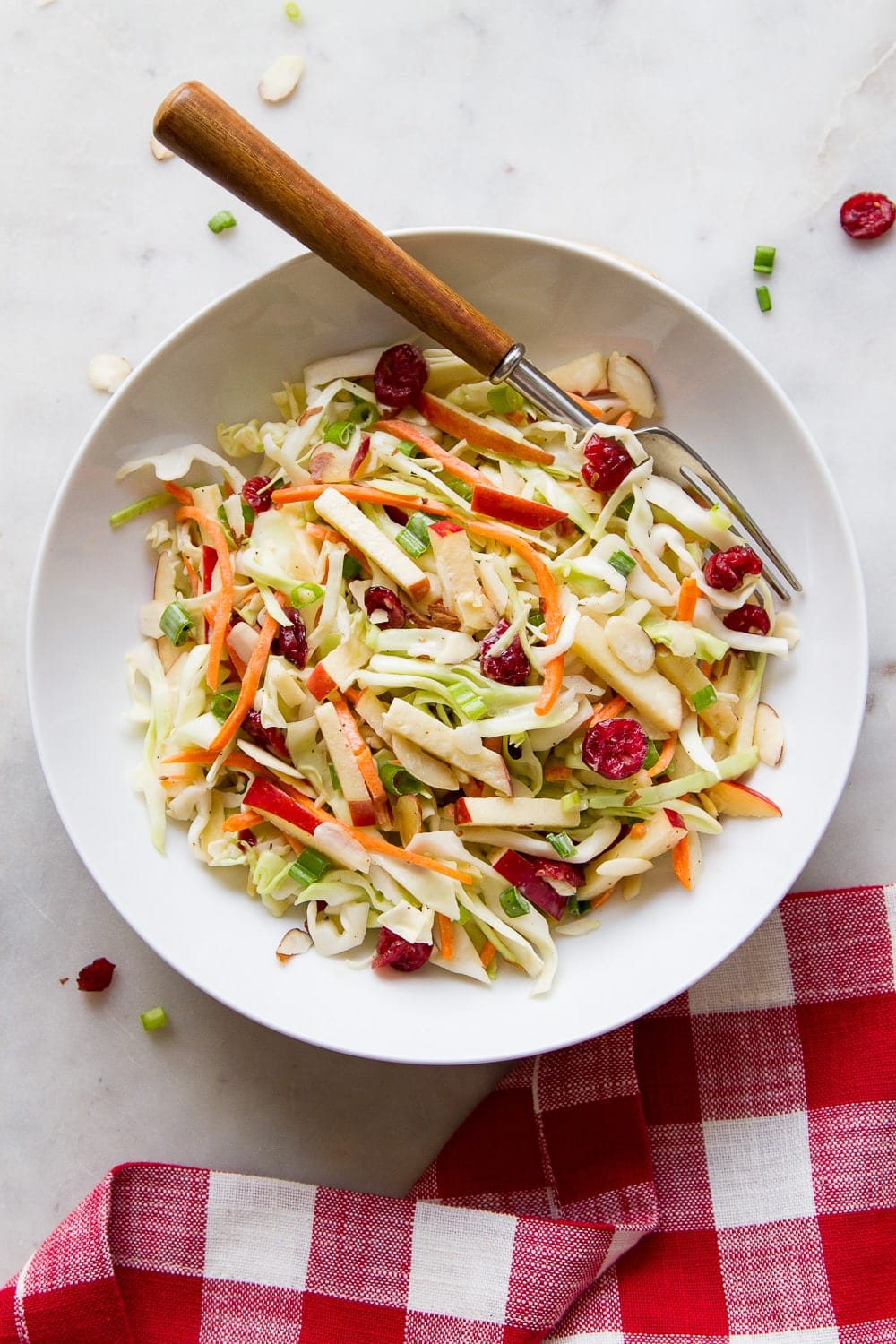 top down view of best apple coleslaw in a white serving bowl with wooden fork.