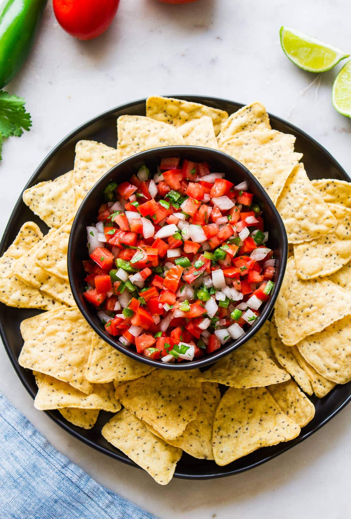 top down view of a bowl with fresh pico de gallo surrounded by tortilla chips.