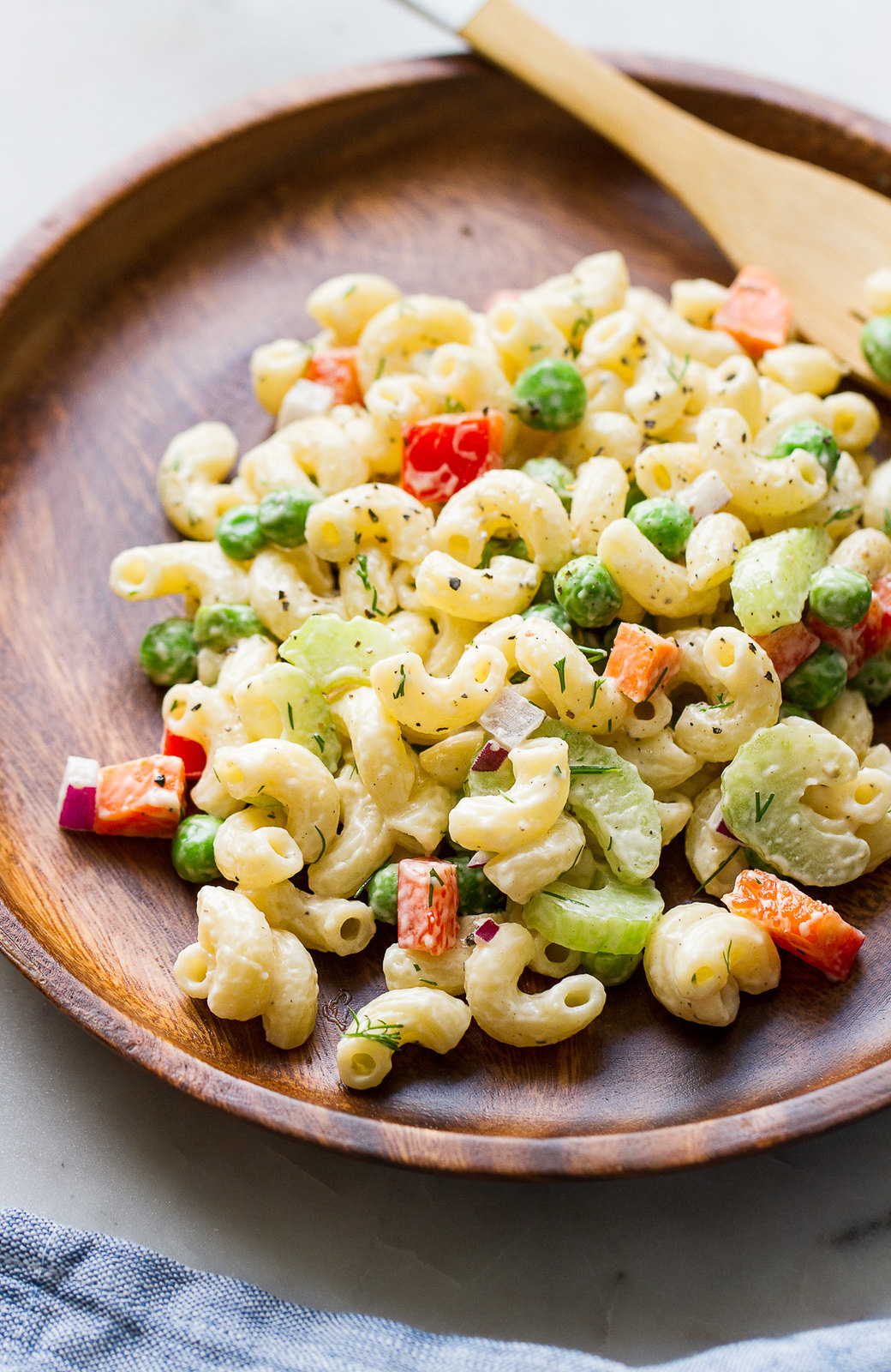 top down view of a serving of creamy vegan macaroni salad in a wooden plate.