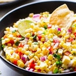 side angle view of simple fresh corn salsa in a black bowl.