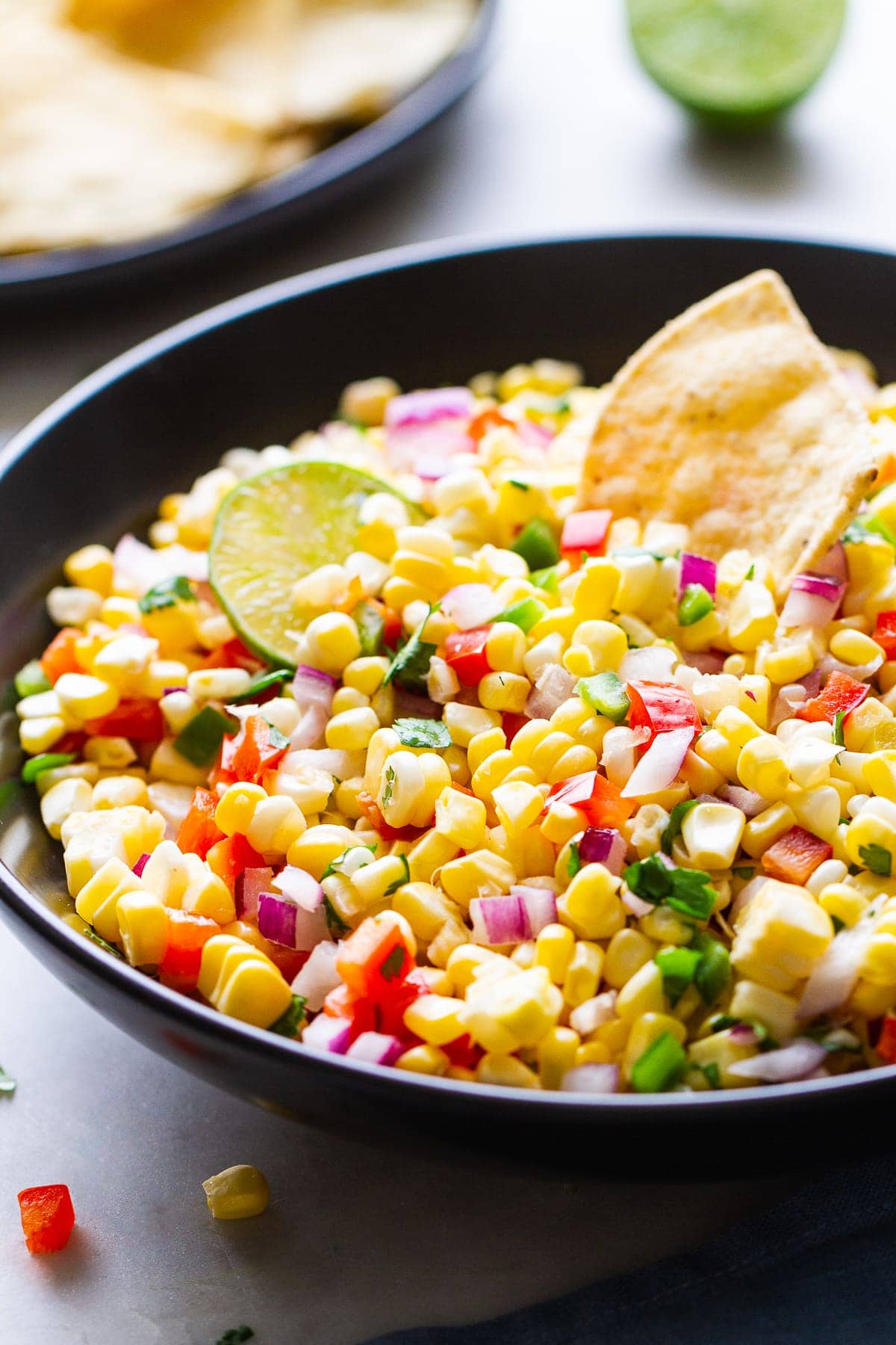 side angle view of simple fresh corn salsa in a black bowl.