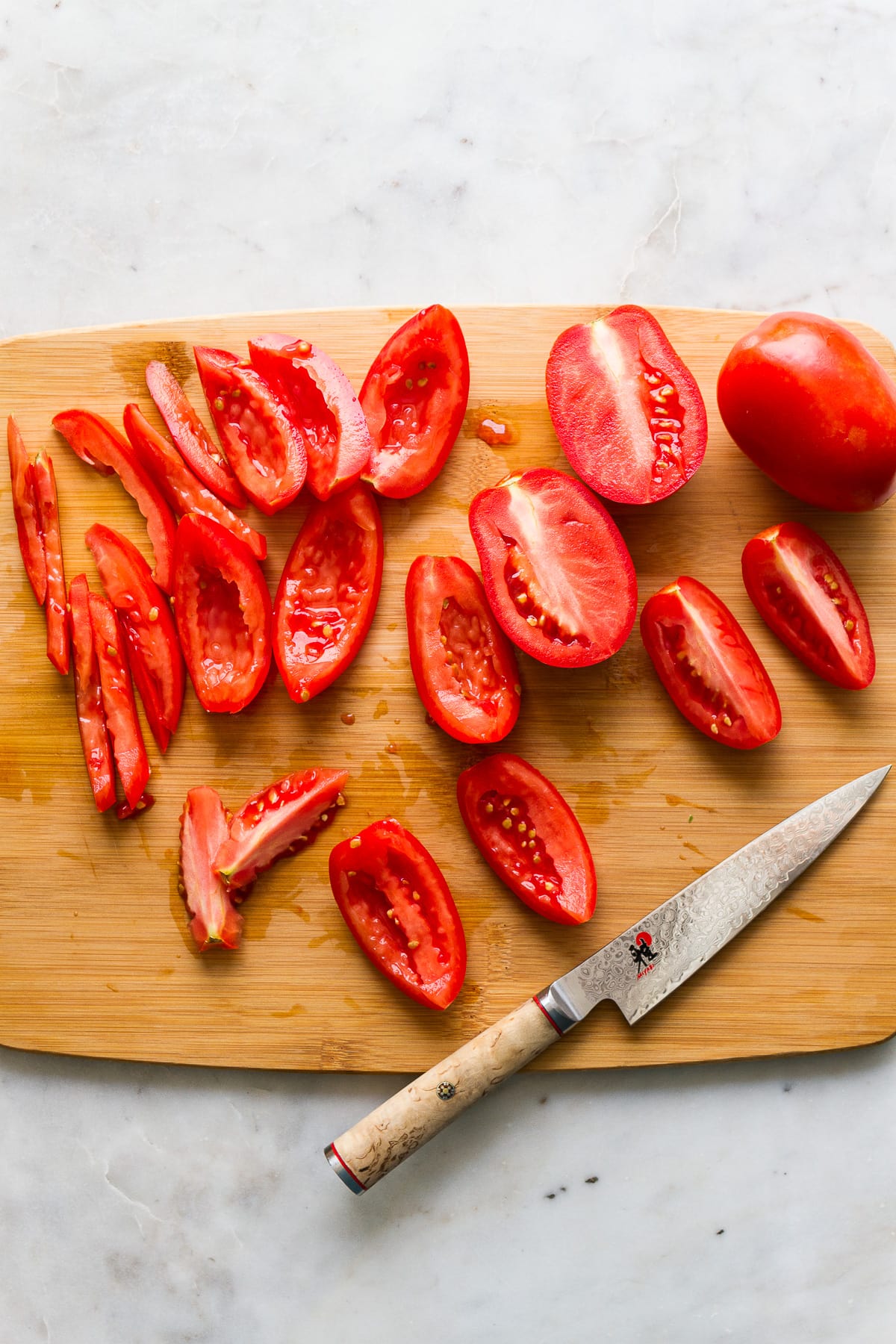 top down view of the process of chopping roma tomatoes for pico de gallo.