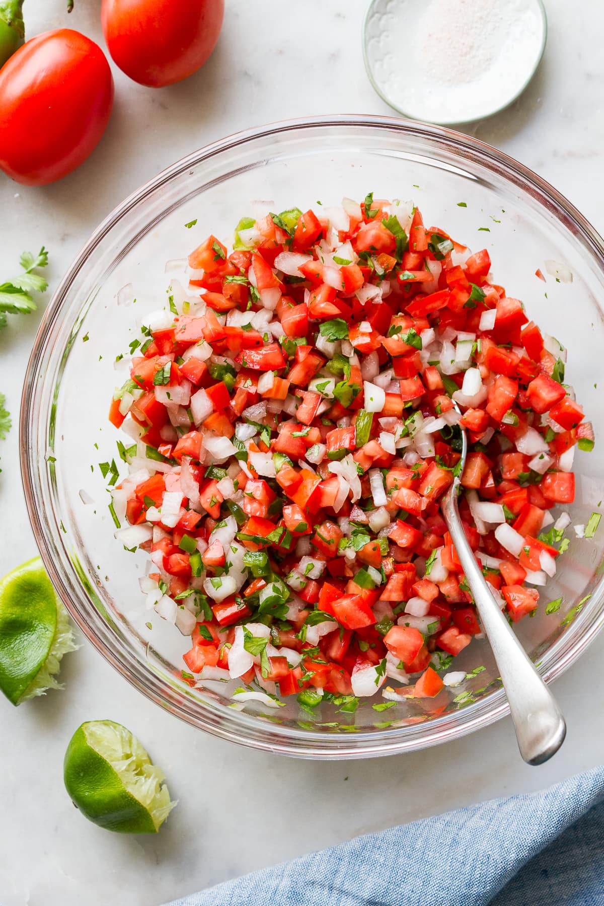 top down view of freshly made healthy pico de gallo in a large mixing bowl with spoon. 