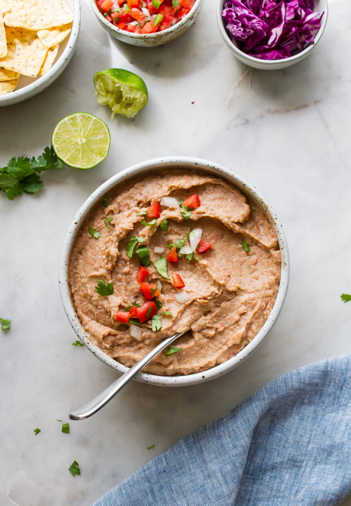 top down view of quick and easy refried beans in a bowl surrounded by items. 