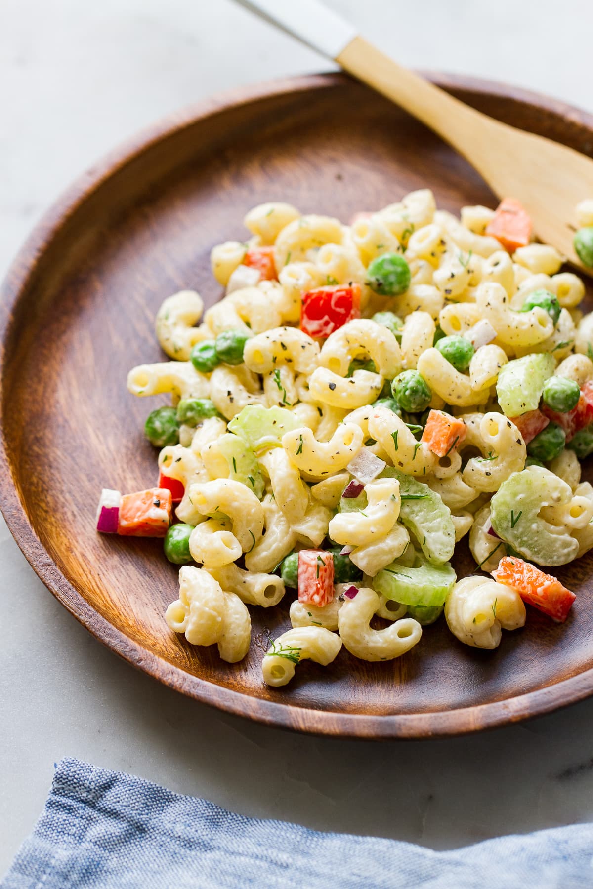 top down view of a serving of creamy vegan macaroni salad in a wooden plate.