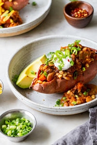 side angle view of chili stuffed sweet potato in a shallow serving bowl.