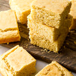 side angle view of slices of freshly made vegan cornbread on a wooden serving board.