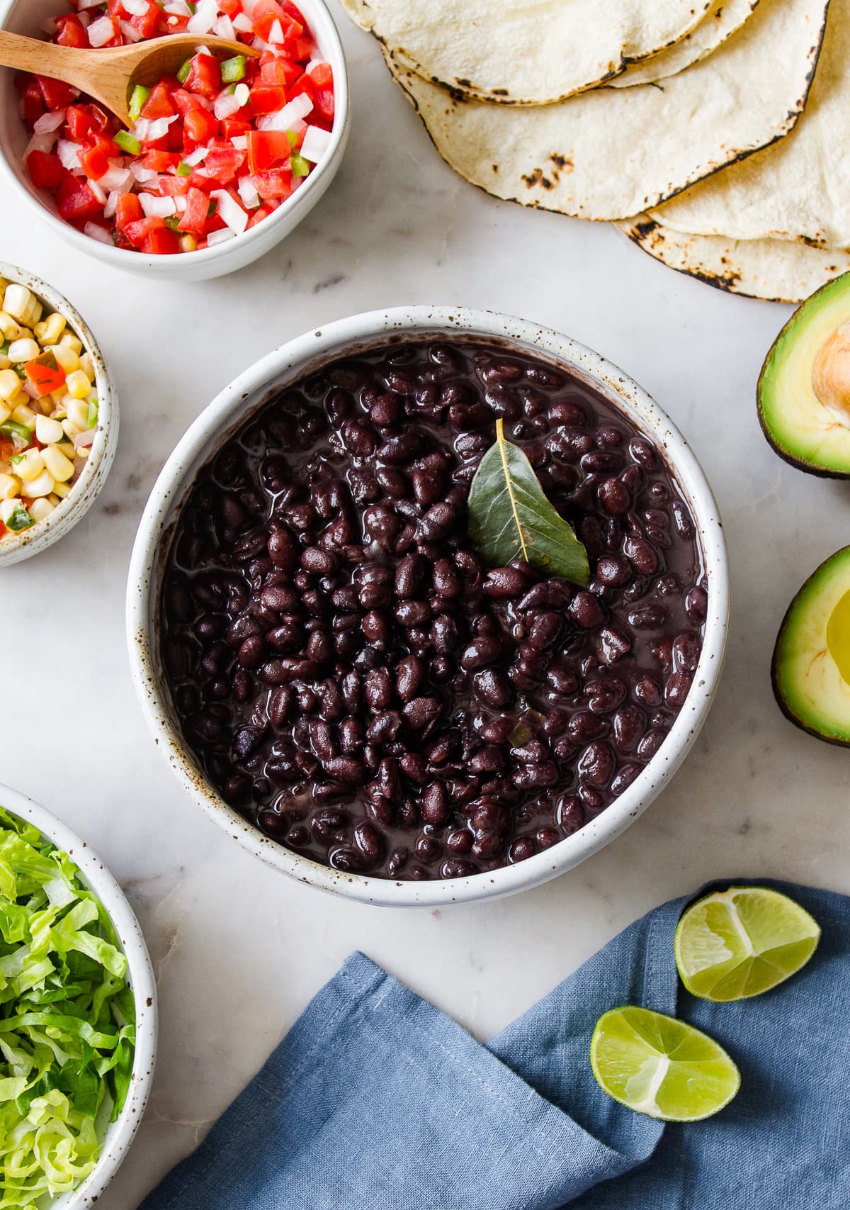 top down view of easy instant pot black beans in a serving bowl with items surrounding.