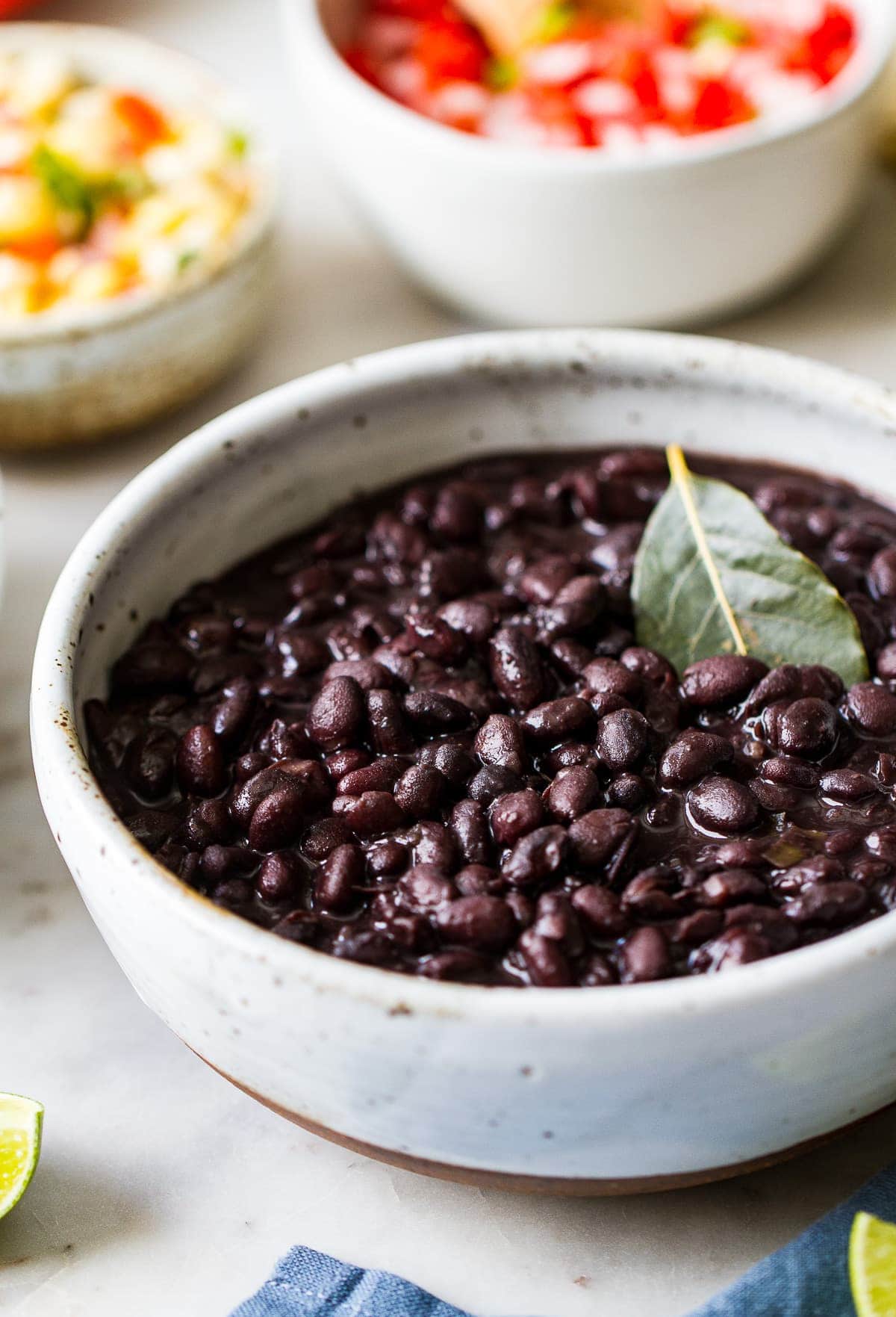 side angle view of easy instant pot black beans in a serving bowl with items surrounding.