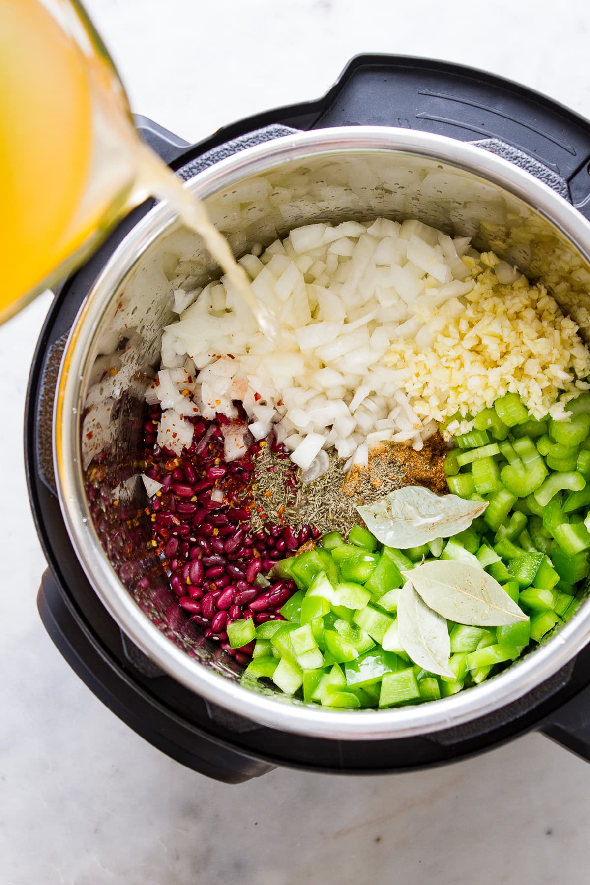 top down view of instant pot filled with ingredients to make healthy vegan cajun style red beans and rice.