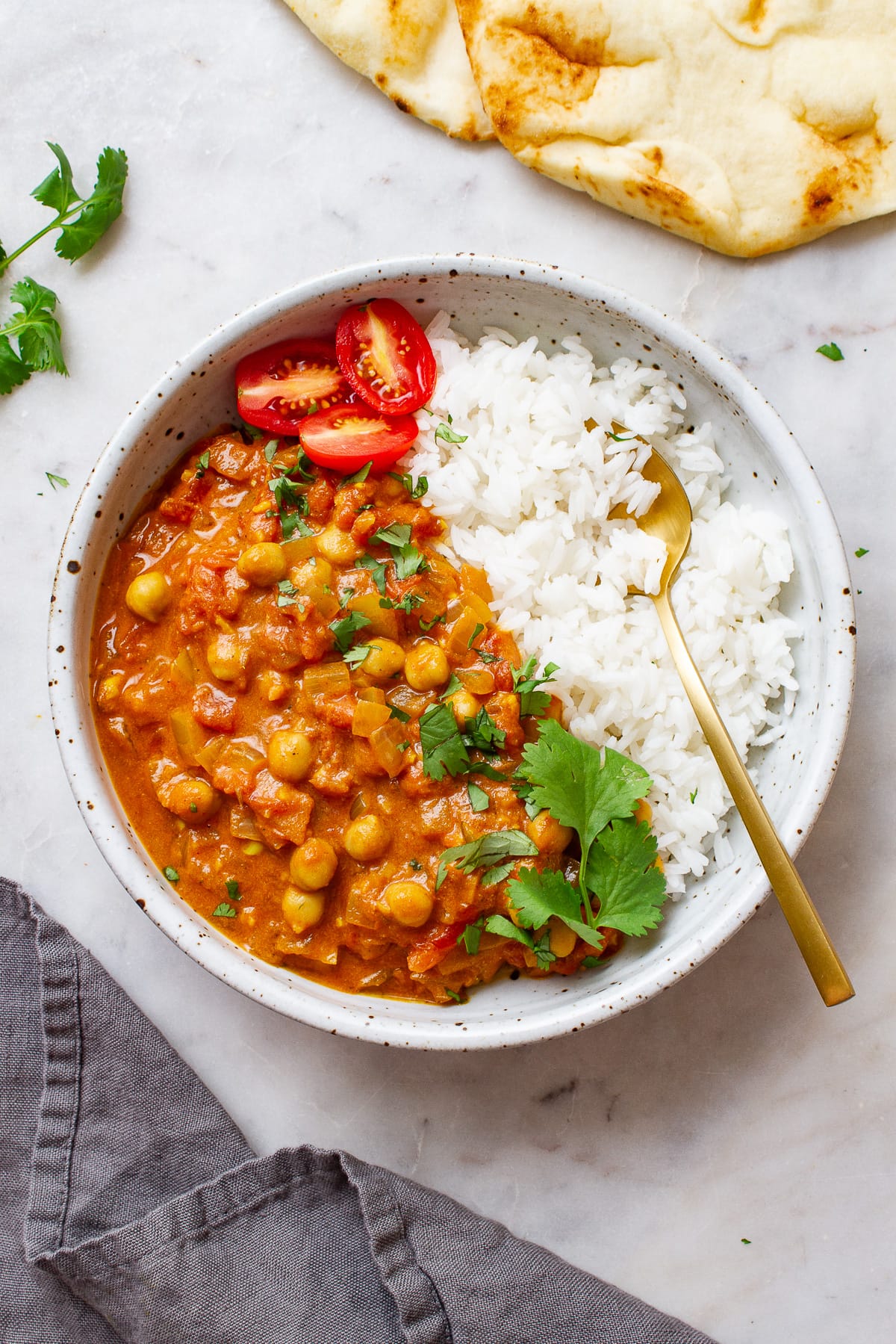 top down view of a bowl filled with a serving of easy vegan chickpea tikka masala and rice in a bowl with spoon.