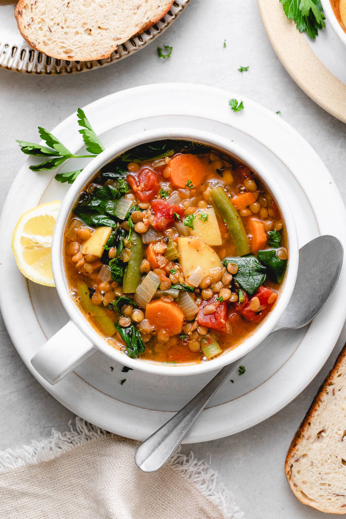 top down view of vegan lentil soup in a bowl with items surrounding.