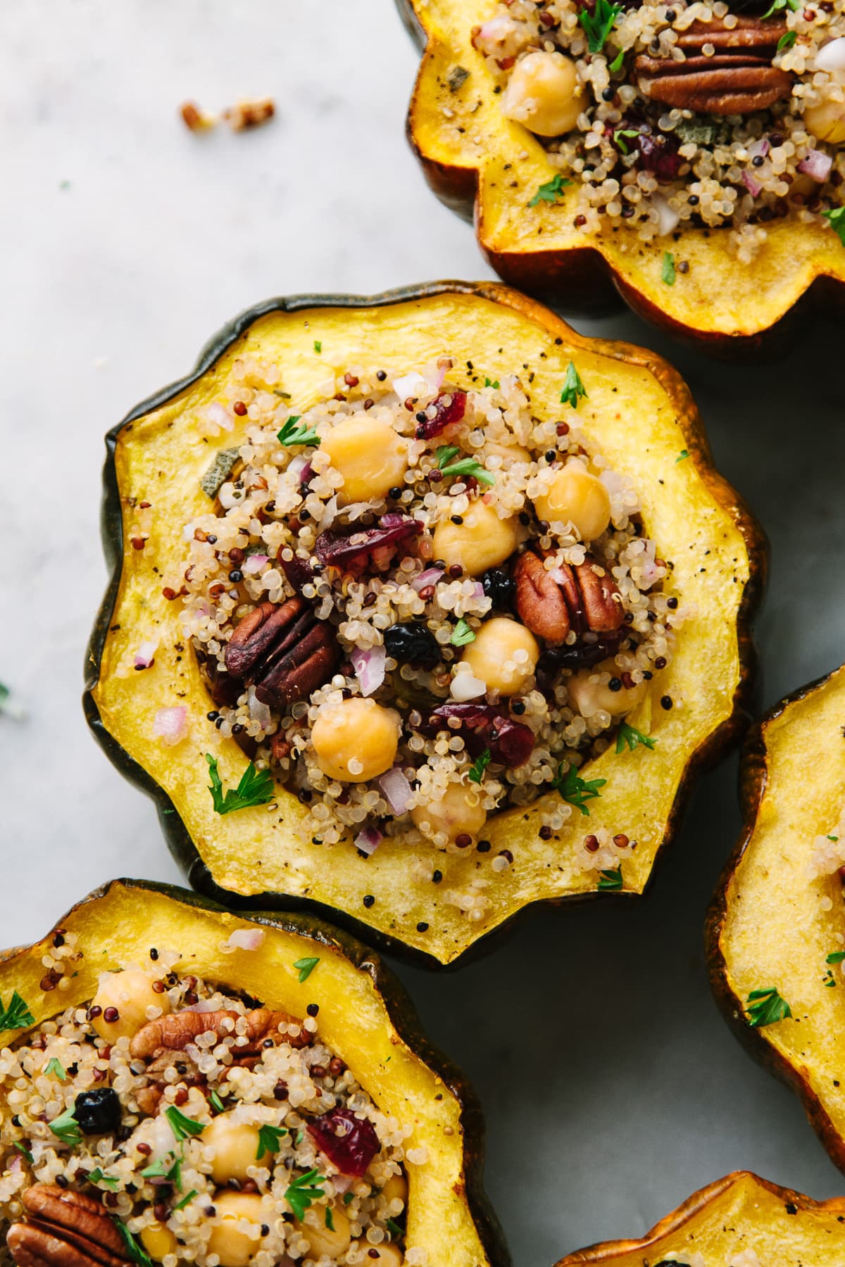 top down view of a group of stuffed acorn squash with quinoa, cranberries and chickpeas.