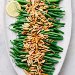 top down view of healthy, vegan green beans almondine on a serving platter.