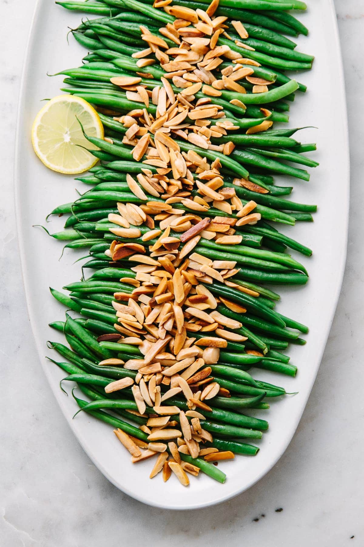 top down view of healthy, vegan green beans almondine on a serving platter.