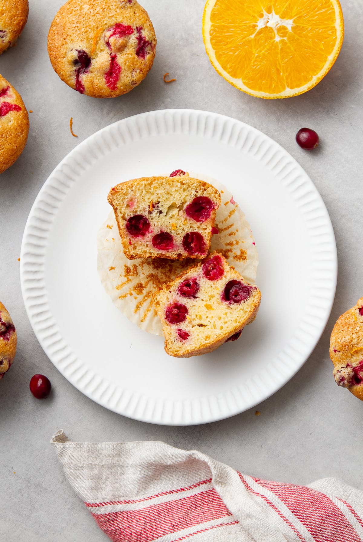 top down view of cranberry orange muffin sliced in half on a small white plate.