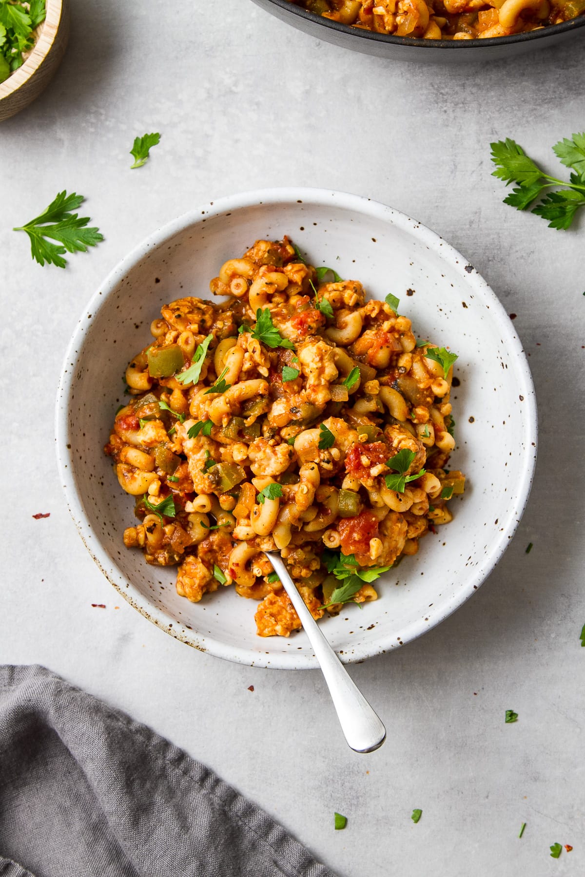 top down view of vegan goulash in a bowl with spoon surrounded by items.