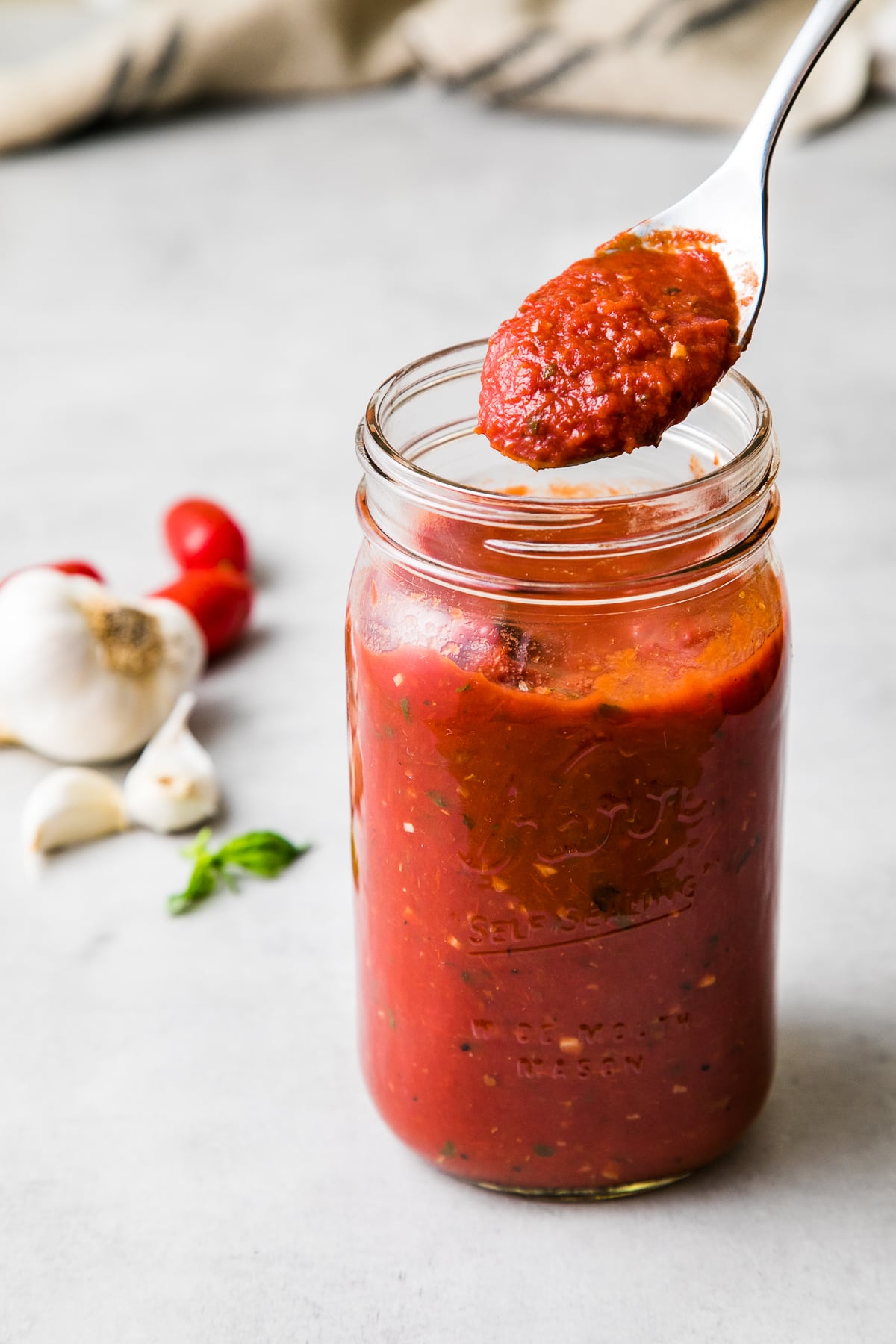 side angle view of jar of homemade marinara sauce with spoonful.