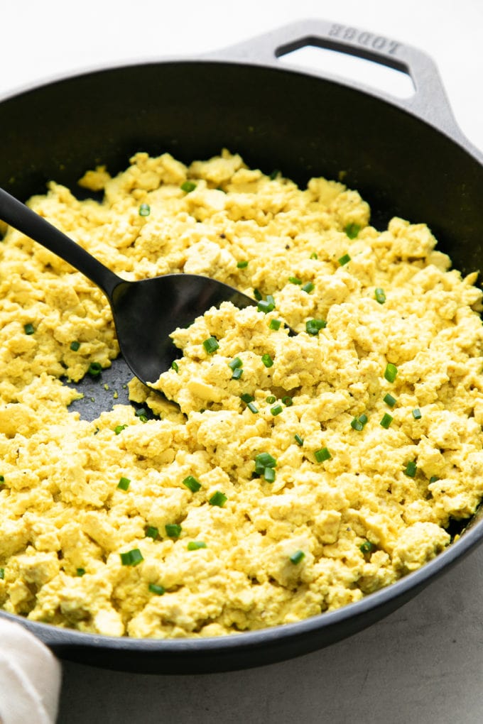 side angle view of freshly made tofu scramble in a skillet with wooden spoon.