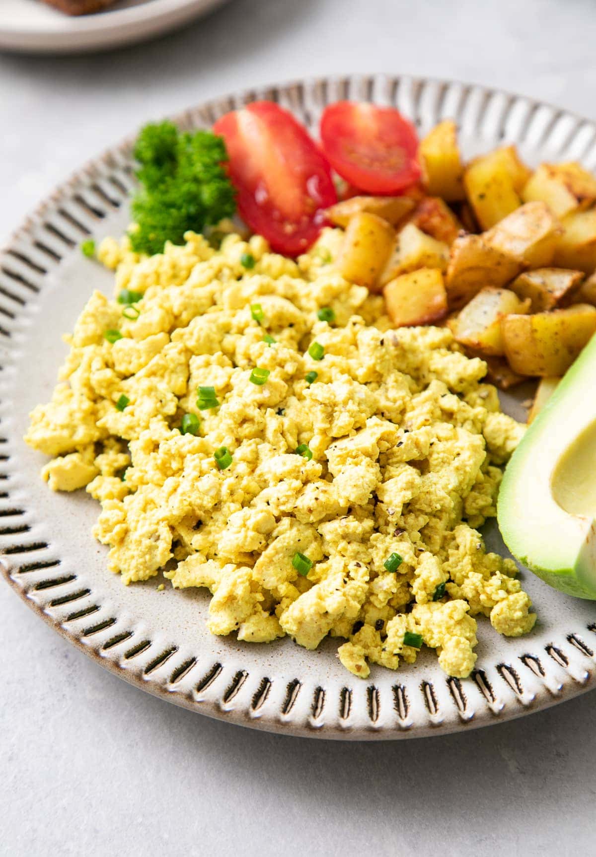 side angle view of a small plate with tofu scramble and items surrounding.