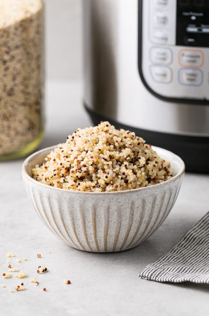 head on view of a bowl filled with quinoa made in an instant pot with items surrounding.