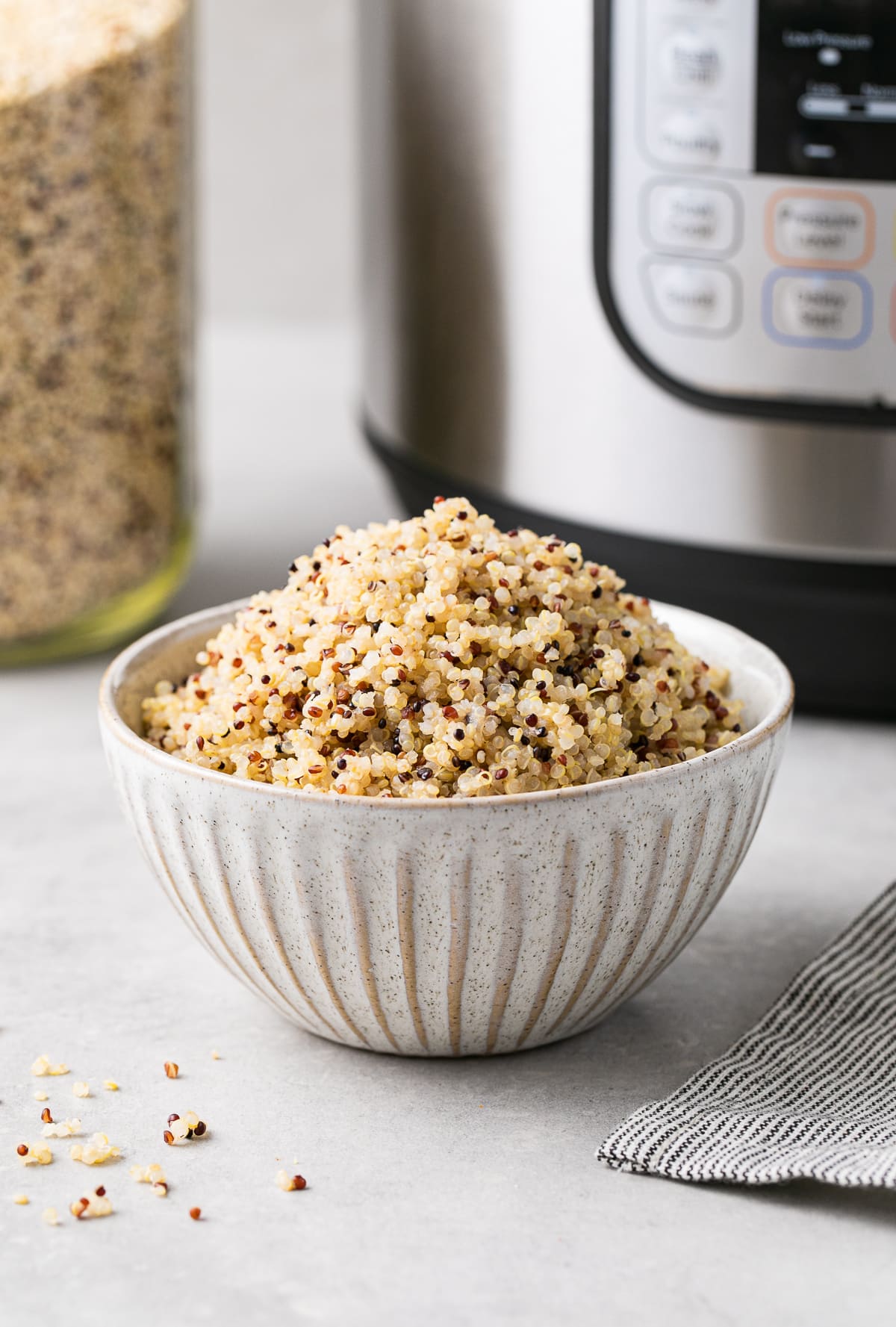 head on view of a bowl filled with quinoa made in an instant pot with items surrounding.