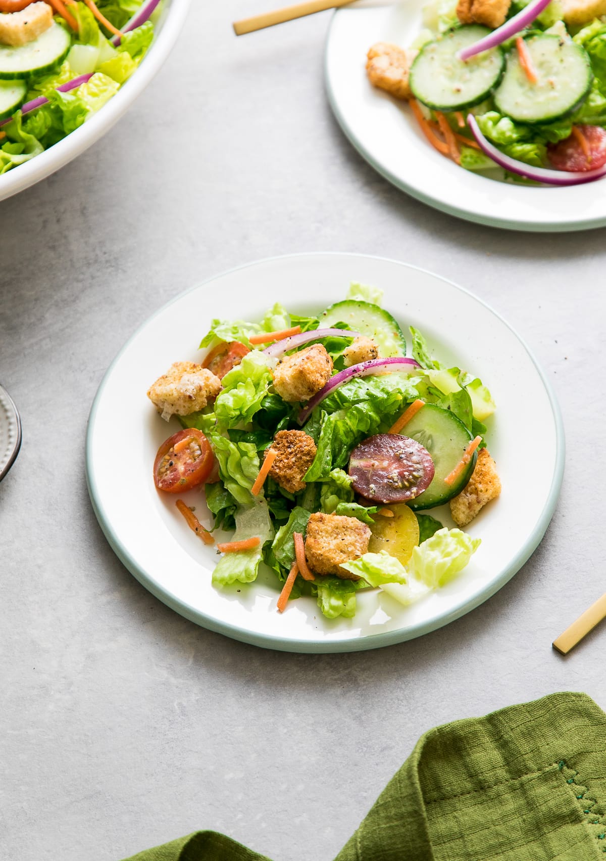 side angle view of house salad on small plate with items surrounding.