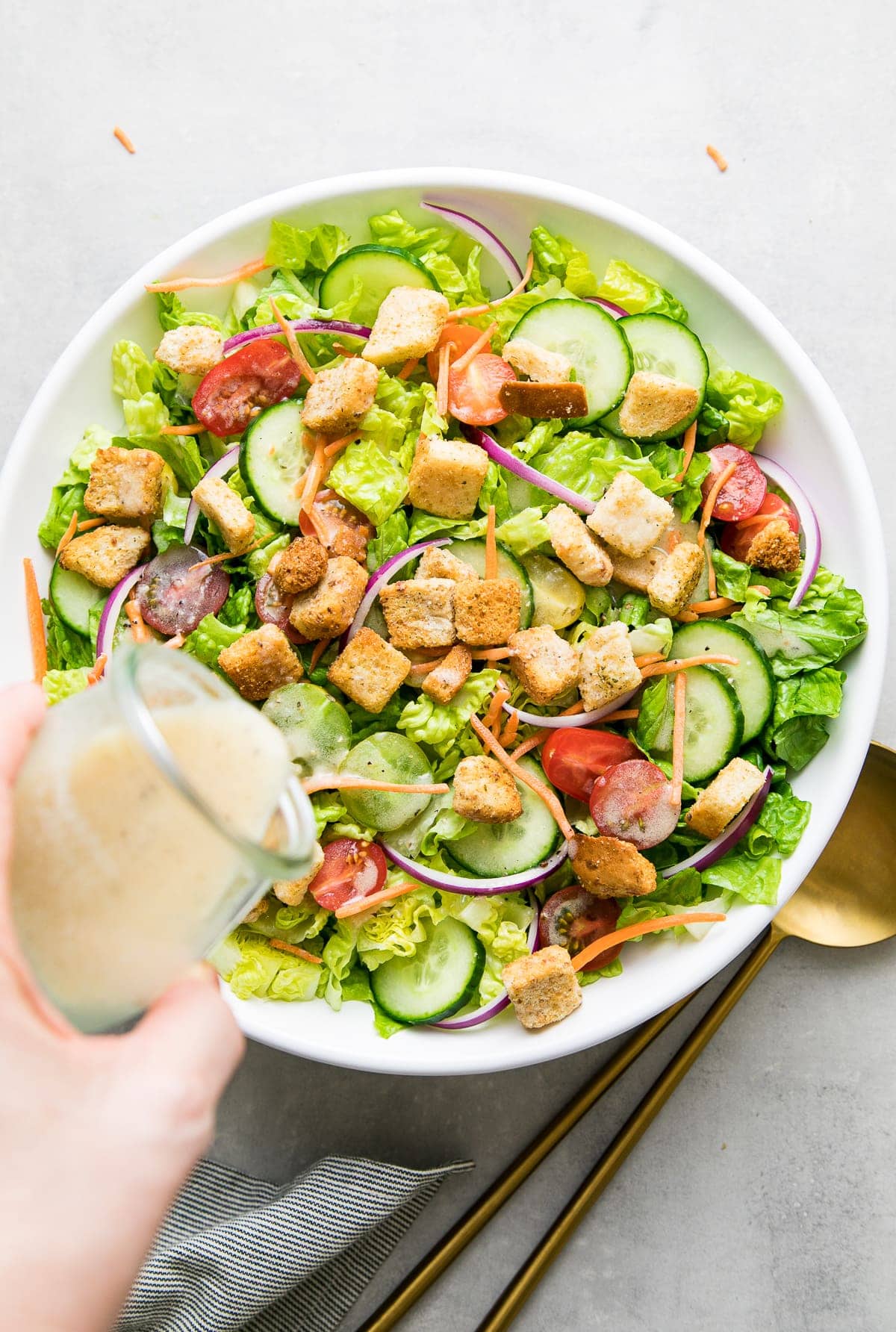 top down view of dressing being poured on house salad.