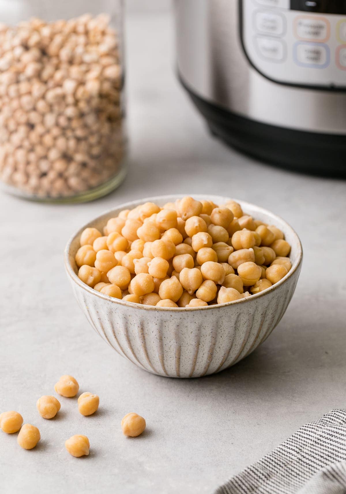 head on view of freshly cooked instant pot chickpeas in a small bowl with items surrounding.