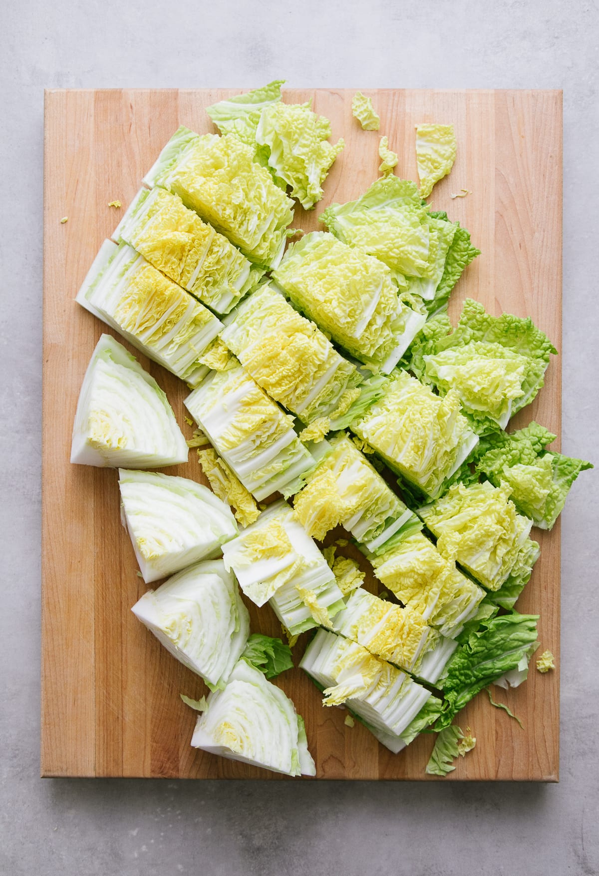 top down view of sliced napa cabbage on a wooden cutting board.