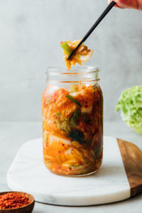 head on view of vegan kimchi in a mason jar with chopsticks.