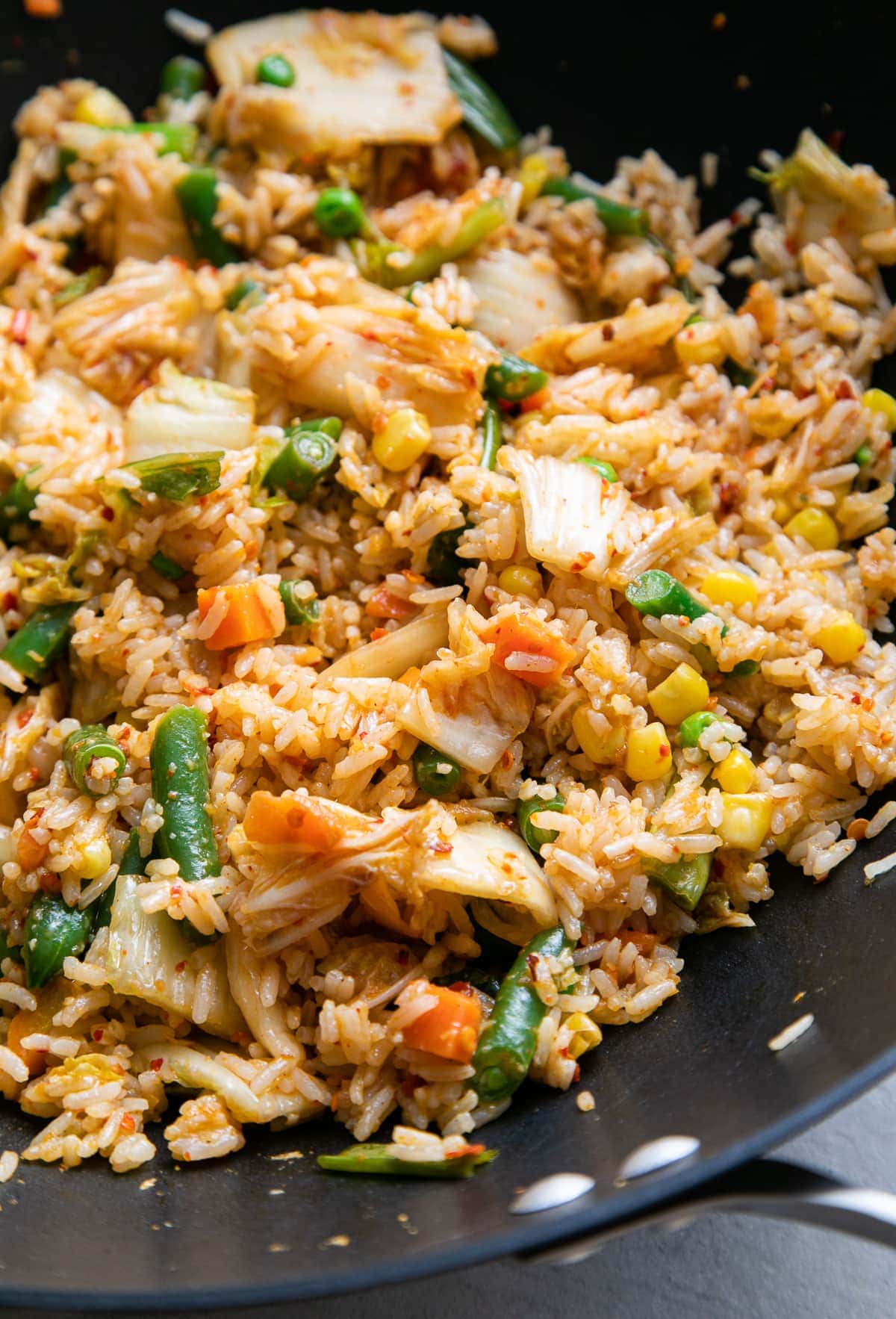 side angle, up close view of vegan kimchi fried rice in a wok.