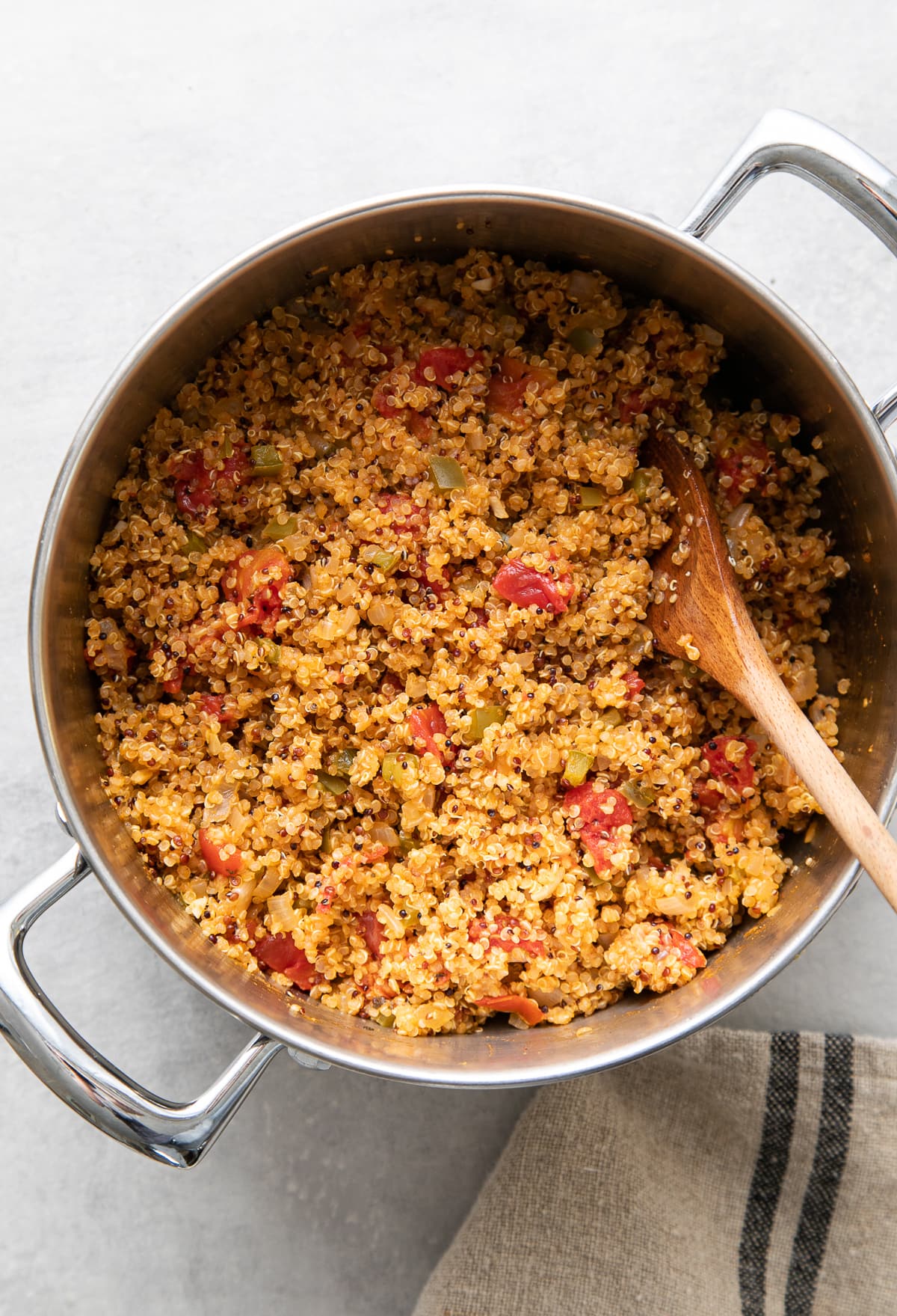 top down view of pot with freshly made quinoa Spanish rice with wooden spoon.