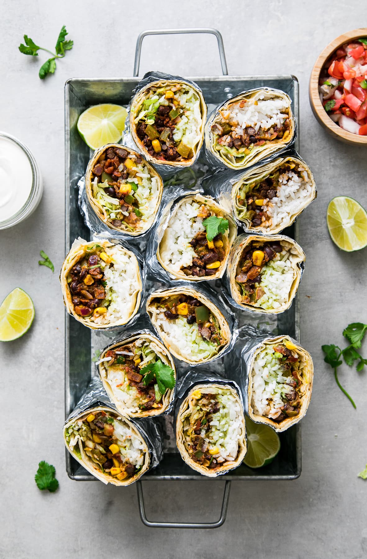 top down view of a bunch of vegan burritos sliced in half and standing with cut side up in a serving tray.