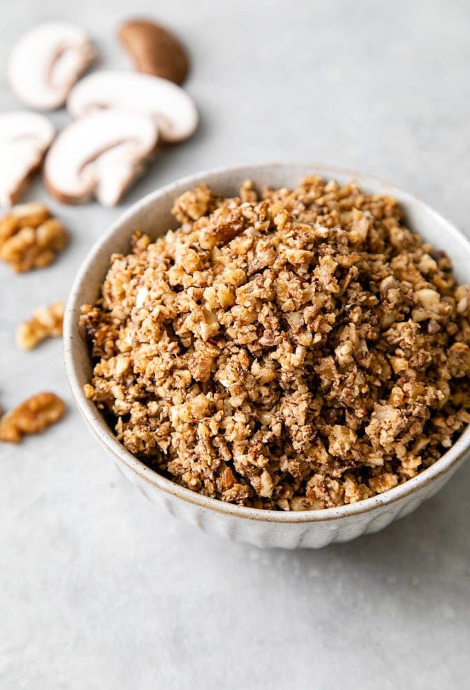 side angle view walnut meat in a bowl with items surrounding.