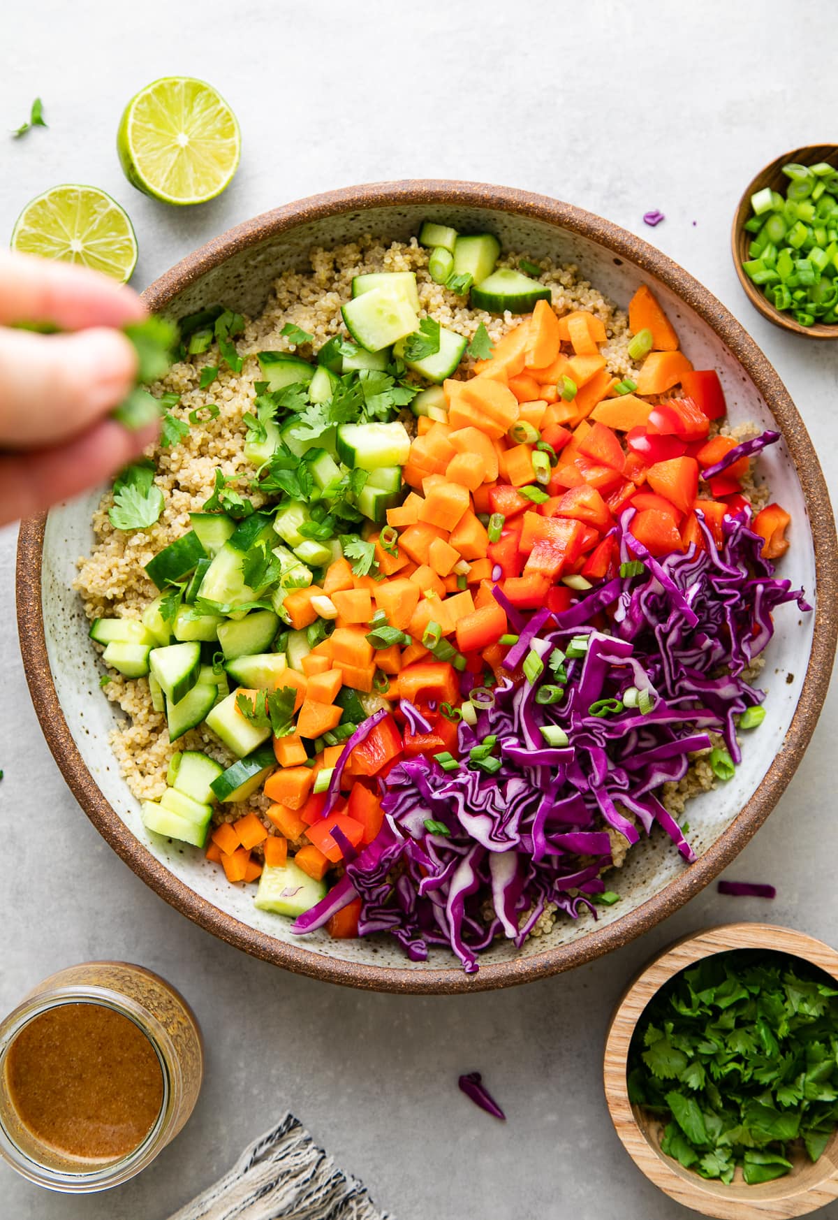 top down view showing the process of making crunchy Thai quinoa salad in a bowl with items surrounding.