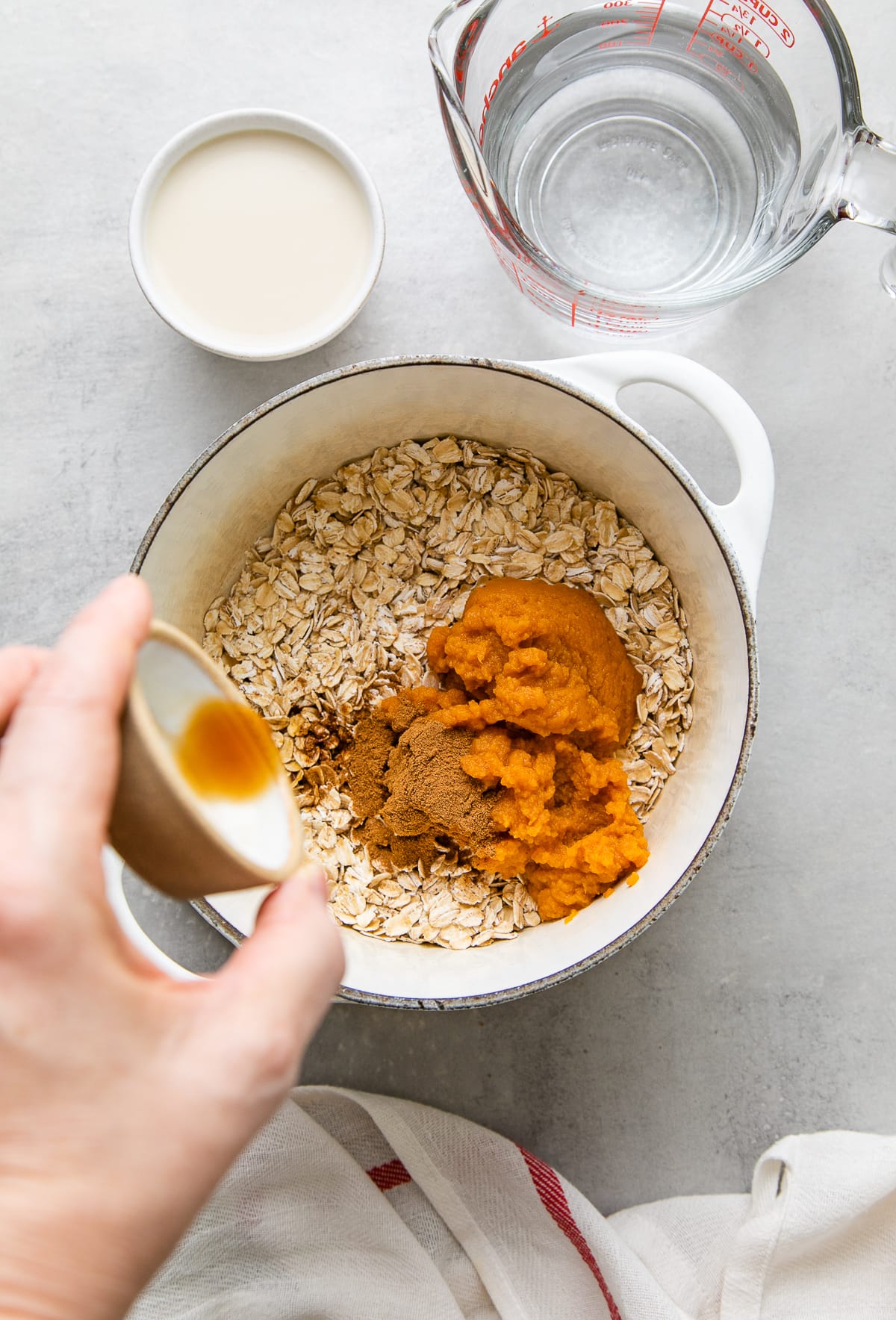 top down view showing the process of adding pumpkin oatmeal ingredients to pot before cooking.