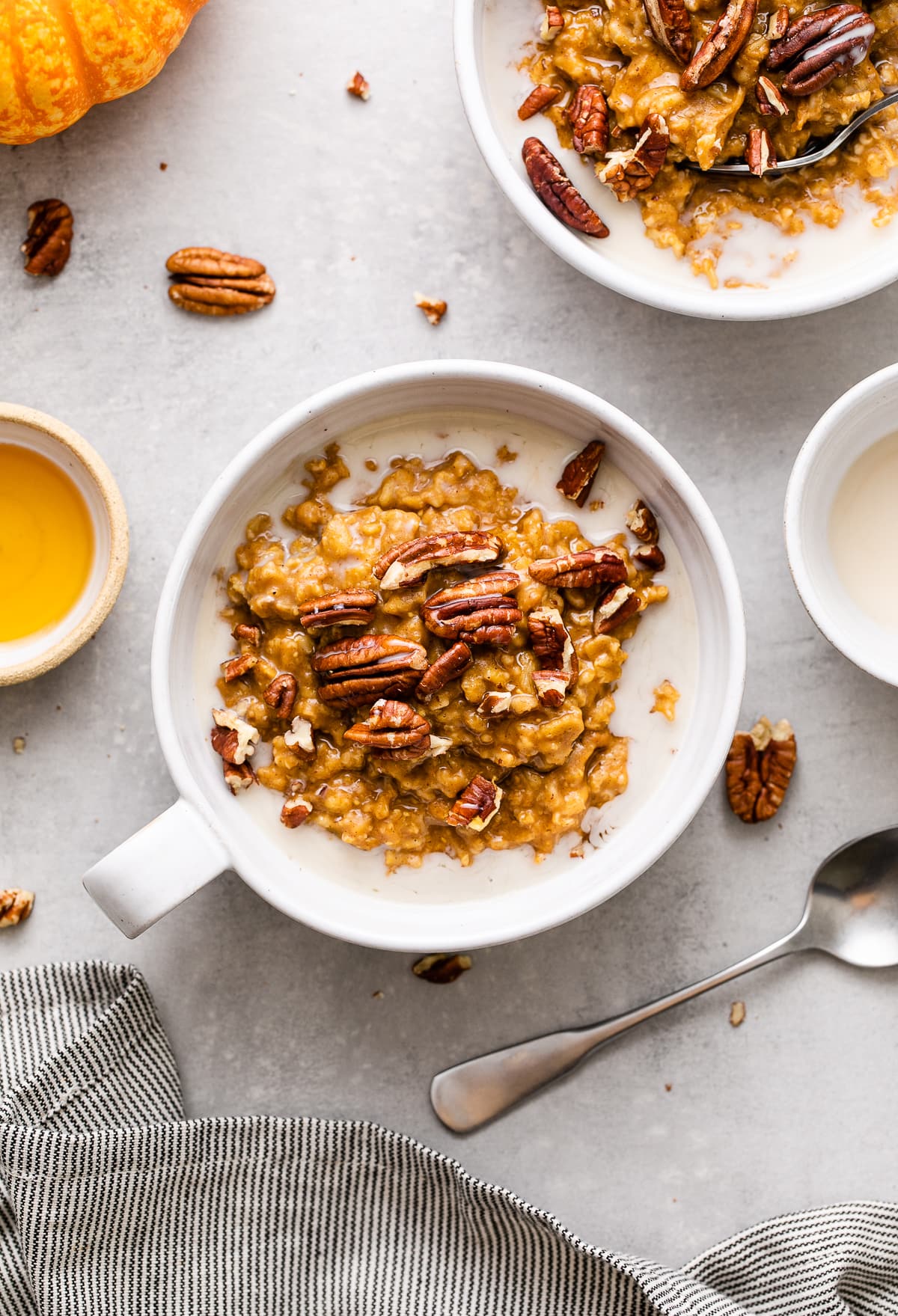 top down view of healthy pumpkin oatmeal in a whole bowl with handle and items surrounding.