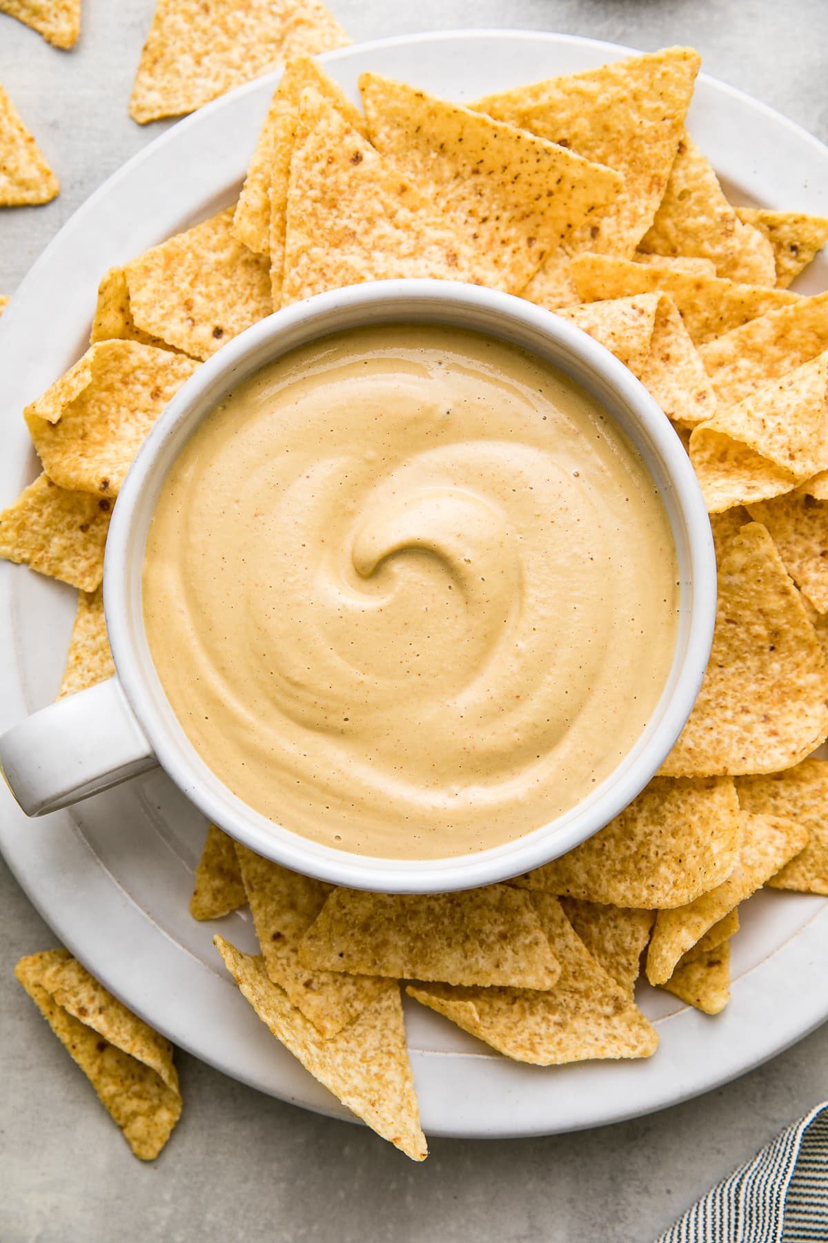 top down view of bowl of freshly made vegan queso in a bowl with chips surrounding.