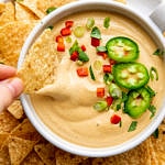top down view of chip dipped into bowl of cashew vegan queso.