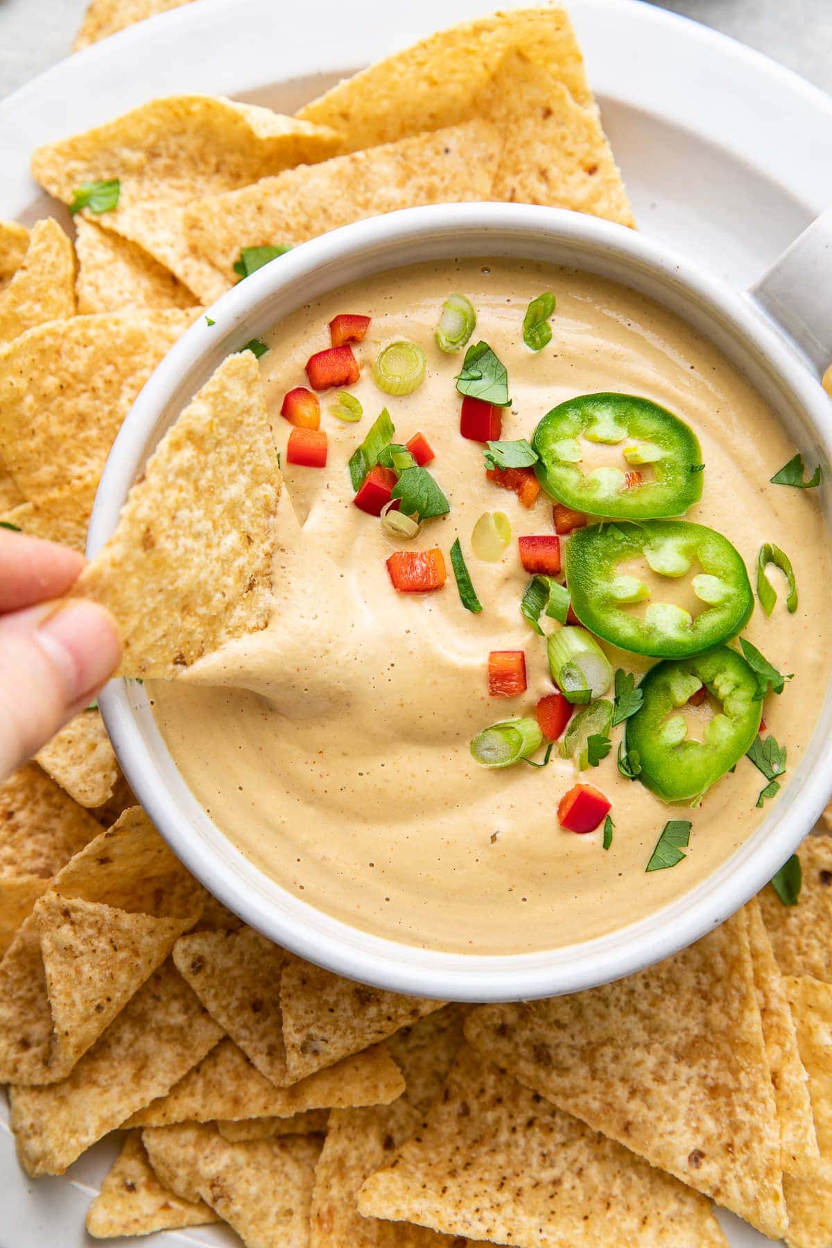 top down view of chip dipped into bowl of cashew vegan queso.