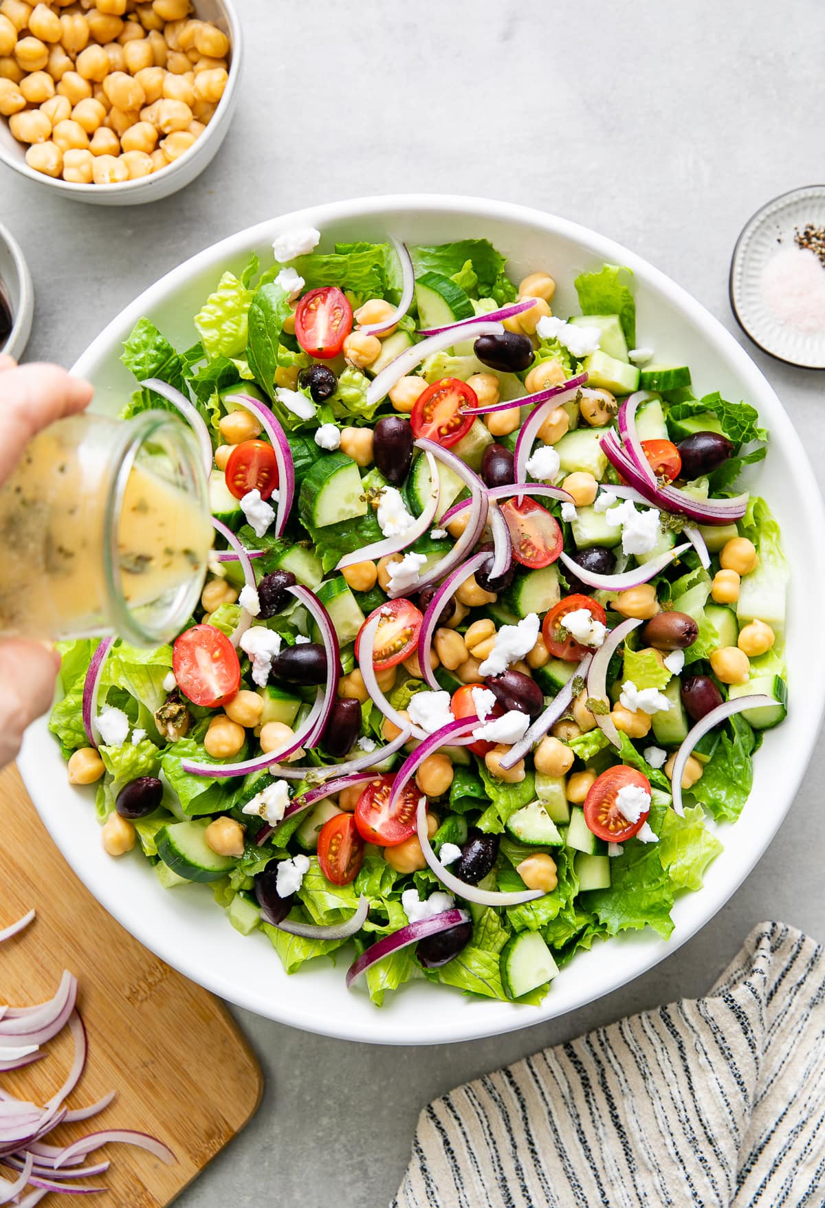 top down view of vinaigrette in glass jar being poured over mediterranean salad.