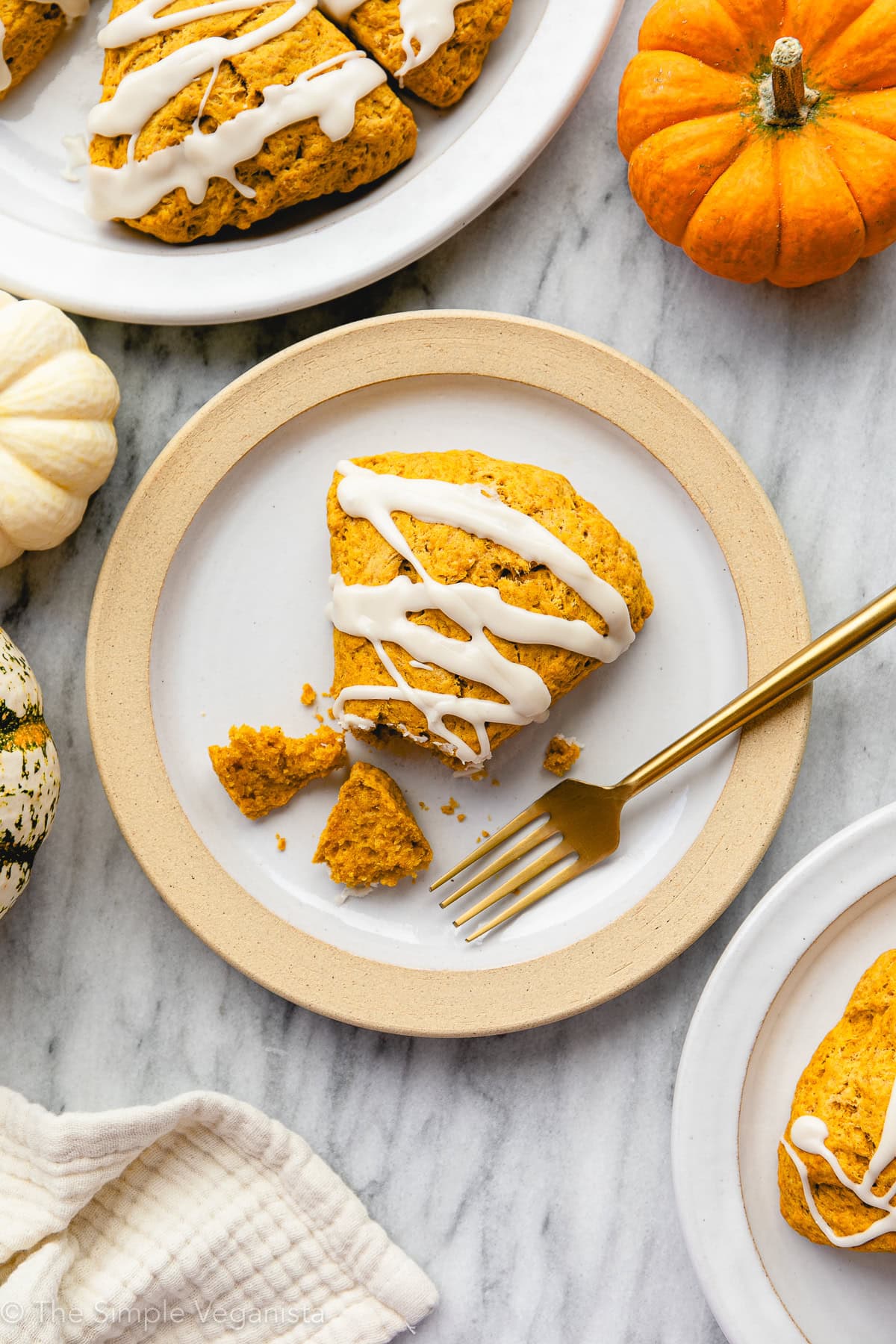 Vegan pumpkin scone on a plate with items surrounding.
