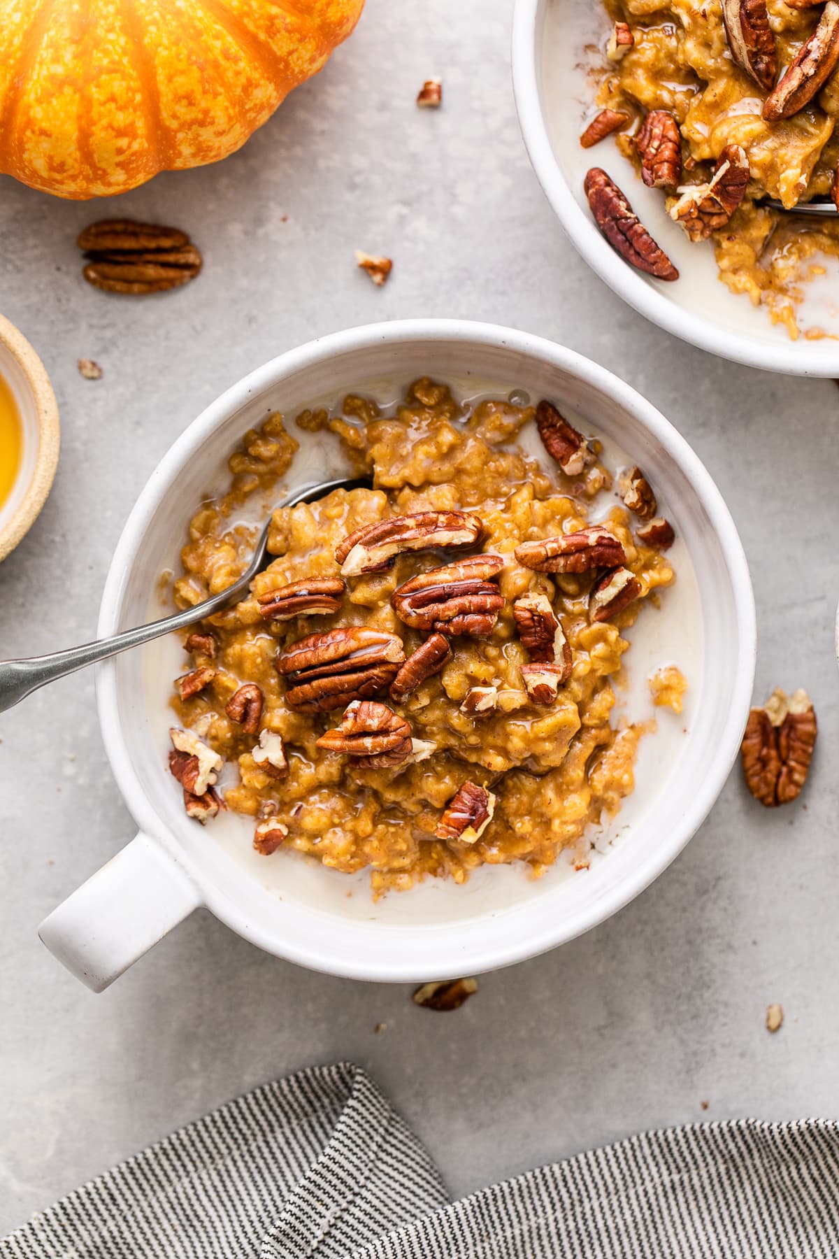 top down view of healthy pumpkin oatmeal in a whole bowl with spoon and items surrounding.
