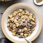 top down view of bowl with serving of vegan mushroom stroganoff with fork and items surrounding.