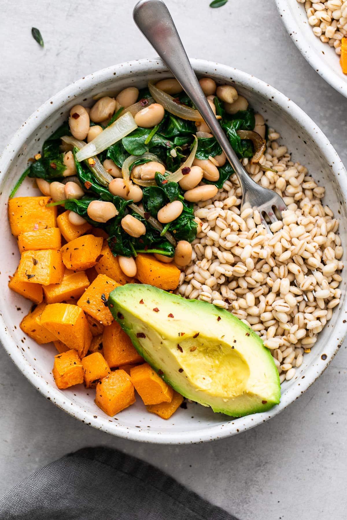 top down view of plated barley bowl with squash, greens, and beans.