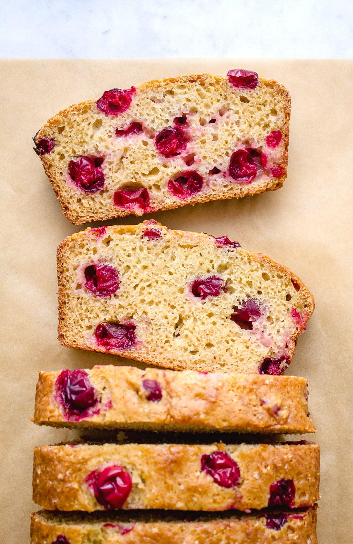 top down view of sliced cranberry orange bread on parchment paper.